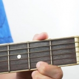 Spelar bm-ackordet på en gitarr