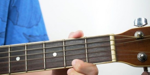 Spelar bm-ackordet på en gitarr